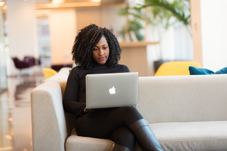 Black woman on couch with laptop