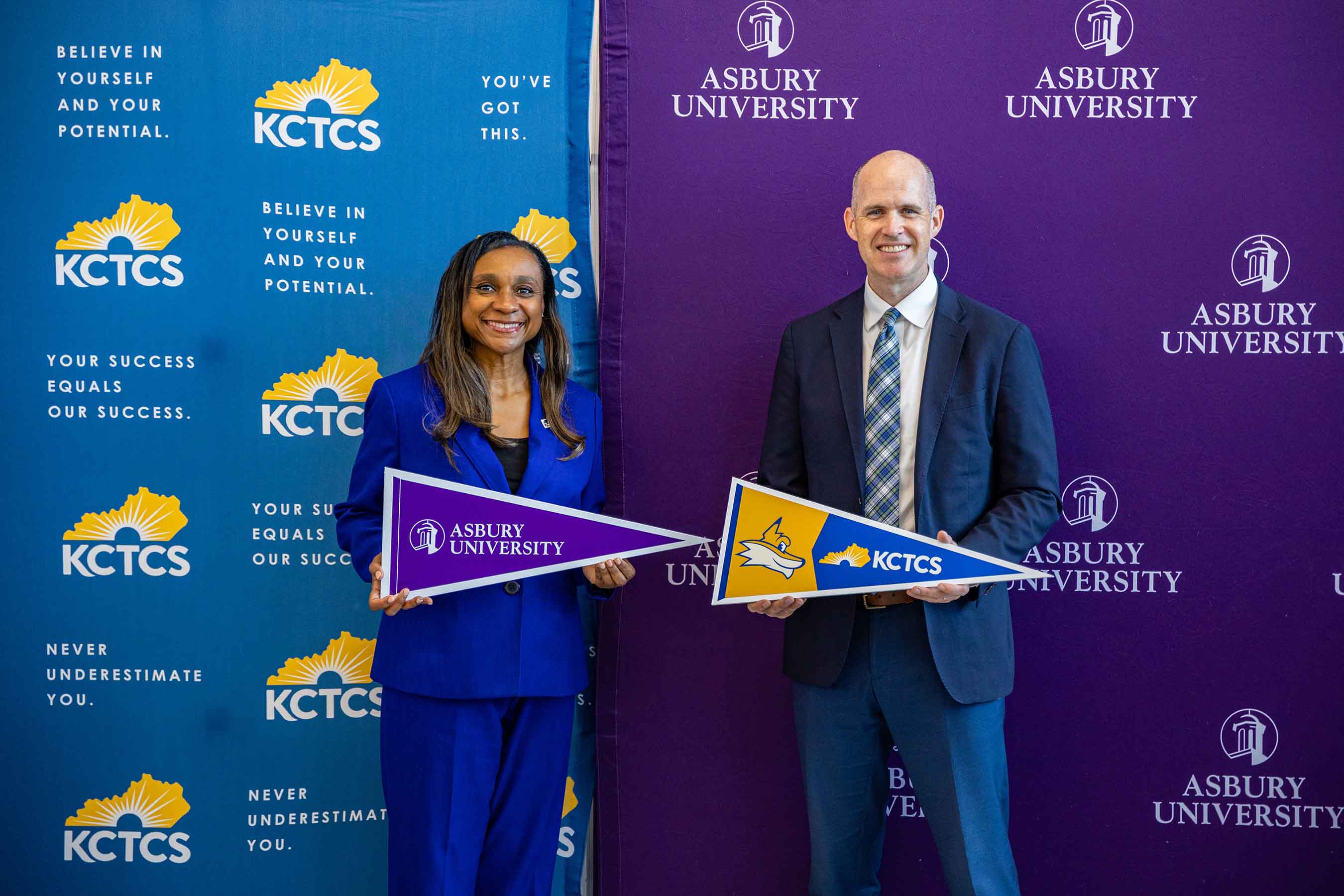 KCTCS’ Acting Provost Reneau Waggoner and Asbury University President Kevin Brown exchange pennants following the signing ceremony.