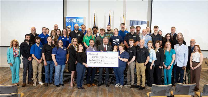 large group of students in 4 or 5 rows with KCTCS president Dr. Ryan Quarles while they hold a large presentation check of $250 for scholarship money