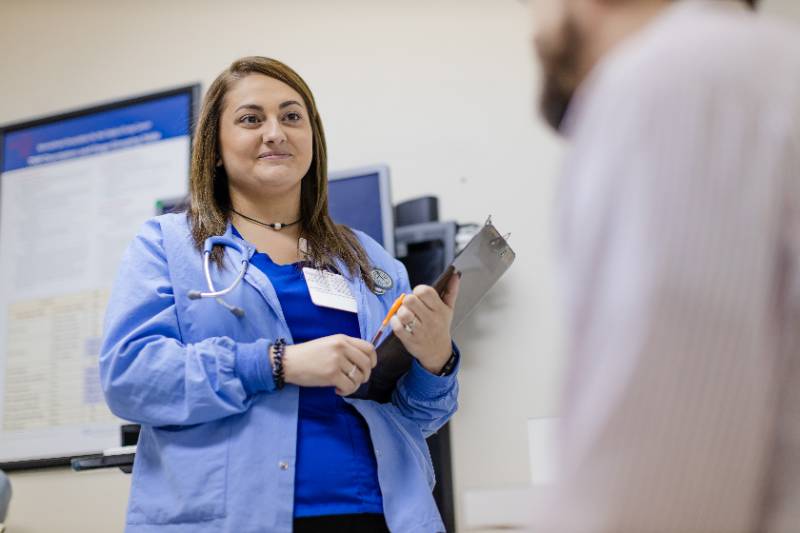 Woman in scrubs listening to what appears to be patient